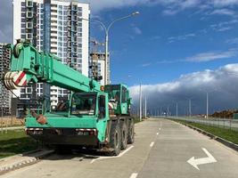 Large powerful new industrial green construction crane used in the construction of new areas of the city. Special construction equipment photo