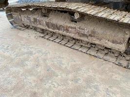 The caterpillar of a excavator or bulldozer stands on a construction site. The steel tracks are covered with dry earth. Close up photo