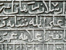 textura de piedra las letras están talladas en una pesada tabla arenosa. fuente antigua, palabras grandes y altas talladas con una línea gruesa y retorcida, la antigua creatividad de las tribus en un tablero gris foto