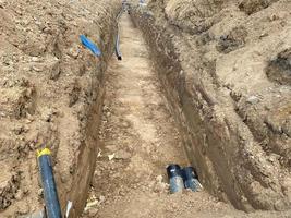 Large industrial modern new large diameter polyethylene plastic water pipes lie in a pit underground at a construction site during a water pipe repair photo