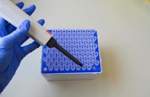 A scientist in a medical laboratory with a dispenser in his hands is doing an analysis photo