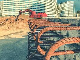 bloque de hormigón con barras de refuerzo oxidadas que sobresalen por dentro. accesorios para la construcción de casas. bloques en el fondo de una excavadora roja foto