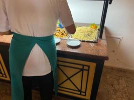 The chef in black apron with a box for a food near the shelf for a buffet with all inclusive photo