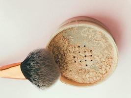 powder brush on a bright pink background. fluffy brush for applying friable textures. brush in powder, applying powder to the skin. masking imperfections and acne photo