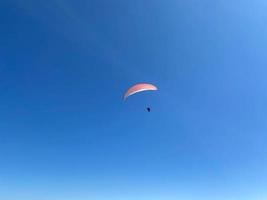 Parachutist is flying slowly down with an open parachute. Skydiving, gliding, parachute jump photo