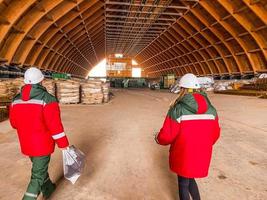 construction of a wooden warehouse. in the warehouse of fertilizers and building materials. workers in uniforms and helmets came to the construction site photo