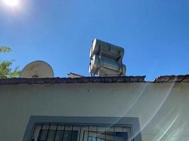 Solar cells on the tiled roof of a residential building. Solar water heating panel and barrels of water on roof. Alternative energy sources, environmental preservation photo