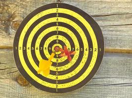 Large playable yellow and black dartboard or darts in the bar against the background of a wooden wall photo