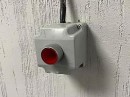 botón rojo de emergencia en una pared blanca foto
