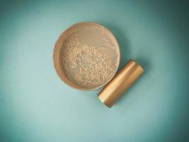 loose powder on a blue background. powder in a pink compact box. comfortable shape, round powder for make-up and create even and matte skin photo