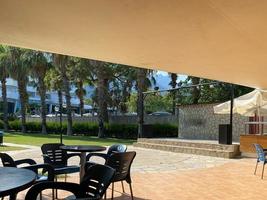 Contrast view of open-air cafe with tables and chairs and background of palms photo