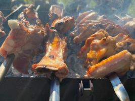 Delicious beautiful fried kebab of pork meat, chicken wings and pork ribs on the smoke cooked on the grill with skewers with coals. Barbecue in nature. BBQ photo