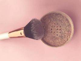 loose powder on a bright background. powder with white handle and gold nap holder. brush made of natural materials. hypoallergenic makeup brush photo