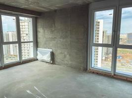 apartment in a new building. concrete blocks, house without repair with bare walls. battery in the room, walls made of gray blocks without finishing, French windows to the floor photo