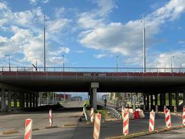 Repair and construction of a road with temporary road signs and cones on the background of a large freeway bridge in a big city photo