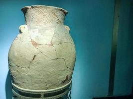 ancient clay vase with cracks. Museum piece. vase with hand-painted top and large cracks. interior vase against a blue matte wall photo