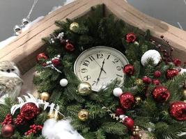 reloj en forma de juguetes navideños sobre un fondo nevado con ramas de abeto. el concepto de navidad foto