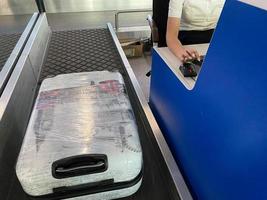 Suitcases travel on a conveyor belt at the airport. Baggage unloaded at the conveyor closeup photo