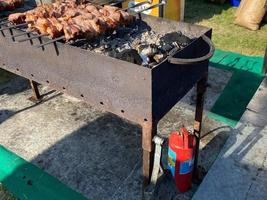 A large iron barbecue and grill barbecue outdoors at the open air at a music festival and a red fire extinguisher photo