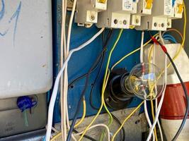 A light bulb in a homemade electric control cabinet for electronic devices with circuit breakers and counters in an iron box photo