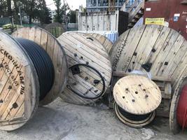 large, wooden, beige spools with coiled black cable. cable for the creation of communications in a new microdistrict of the city under construction photo