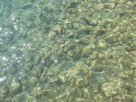 viejas piedras grandes bajo agua clara. fondo natural de piedras en el fondo de un lago, río. una roca debajo de la superficie del wat foto