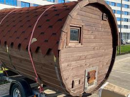 A large round mobile unusual bath or sauna in the form of a trailer for a car in the courtyard of the house for parking photo