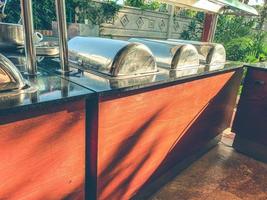 buffet at the hotel. mini-bar with a wide selection of dishes, large cauldrons with food for tourists. wooden rack with dishes of the day under a metal lid photo