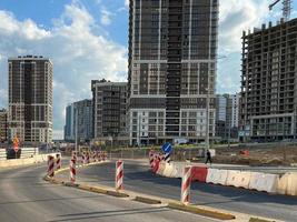 reparación y construcción de una carretera con señales de carretera temporales y conos en el fondo de hermosos edificios nuevos y altos en el fondo del cielo azul y el arco iris en una gran ciudad foto