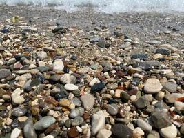 Close up of the wet pebbles those are washing with the sea wave with bokeh photo