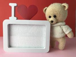 un regalo para una niña el 14 de febrero. oso de punto suave sobre un fondo rojo con un lindo marco en blanco. regalo romántico sentimental para una niña foto
