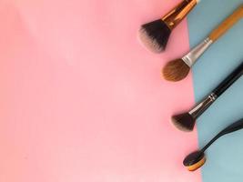 tassels on a stylish pink and blue background. place of work of the makeup artist. against the background different brushes for applying tone, powder and blush photo