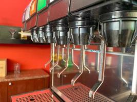 Soft drink dispenser. A soft drink is a drink that typically contains carbonated water, a sweetener, and a natural or artificial flavoring photo