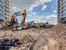 construction of a new neighborhood. laying communications, pipes on the ground for sewerage. against the background of an excavator and other construction equipment for digging photo