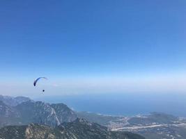 parapentes volando desde la cima de la montaña tahtali cerca de kemer, provincia de antalya en turquía. concepto de estilo de vida activo y aventura deportiva extrema foto