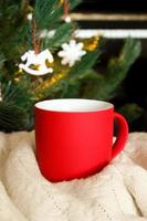 Blank red mug with christmas tree and piano on background,mat tea or coffee cup with christmas and new year decoration,vertical mock up with ceramic mug for hot drinks,empty gift print template photo