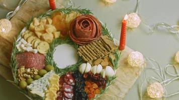 Flat charcuterie with salami, different kinds of cheese. It has dried fruits, various nuts and honey. Holiday arrangement with burning candles video