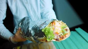 Very large burrito with avocado and chorizo meat. Filming in a romantic setting. Macro shooting video