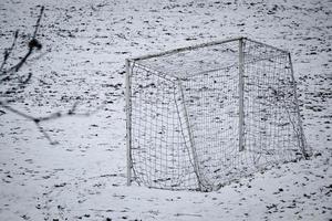 puerta de fútbol solitaria con una red sobre la nieve en el campo de fútbol sin gente jugando el día de invierno foto