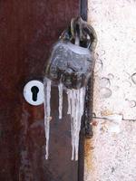 Closeup of old rusty lock frozen with icicles photo