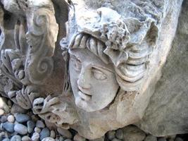 Stone carving of ancient amphitheatre in antique town Myra. Stone portrait of young man. photo