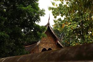 View on a Buddhist temple between trees. Chiang Mai, Thailand. photo