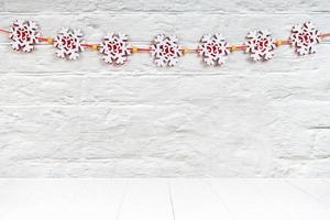 Christmas background with red felt snowflakes garland on white brick wall. Mockup with copy space photo