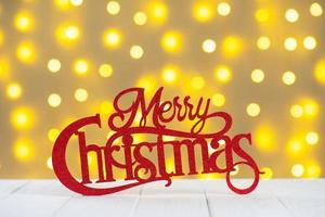 Red wooden glitter lettering Merry Christmas on yellow blurred light bokeh background. photo