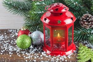 Lantern and Christmas tree over snow on wooden background photo