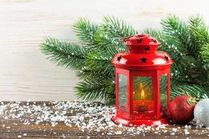 Lantern and Christmas tree over snow on wooden background photo