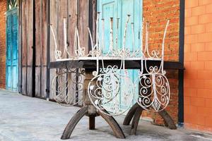 Old wooden table with white vintage chairs on a background of brick wall and colorful wooden doors. photo