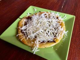 mariam bread with chocolate and cheese topping, served on a green plate photo