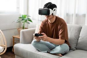 concepto de tecnología una persona que usa un auricular de realidad virtual y sostiene un juego de consola negro mientras está sentado en el sofá foto