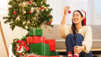 Christmas celebration concept, Young asian woman holding red ball to decorating in christmas tree